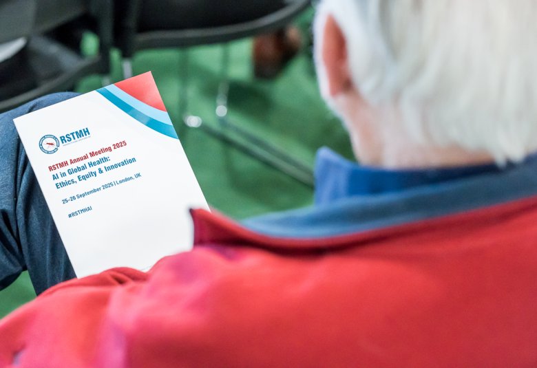 A photo looking over someone's shoulder who is reading the Annual Meeting 2025 Programme.