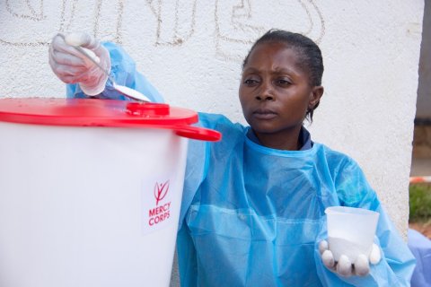 Beni, North Kivu, DR Congo. Kavira Safari Esperance, a hygienist at the Malepe Health Center, has attended the Mercy Corps promoted hygiene awareness outreaches against Ebola. She is using chlorine to disinfect the water used to wash hands. © Mercy Corps