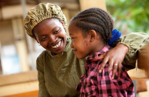 An older woman puts her arm around a younger woman Credit: Geoff Bugbee/Orbis Caption: Orbis-trained Integrated Eye Care Worker Tsehay comforts 13-year-old Asegedech, who is suffering from severe trachoma. Gamo Gofa, Ethiopia. 