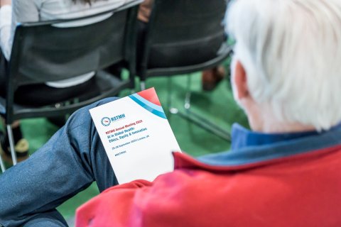 A photo looking over someone's shoulder who is reading the Annual Meeting 2025 Programme.