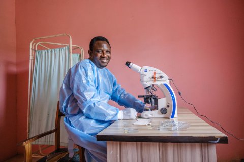 A scientist sits in front of a microscope, at a lab desk at Primary Health Post at Irele Local Government area in Ondo State, Nigeria.